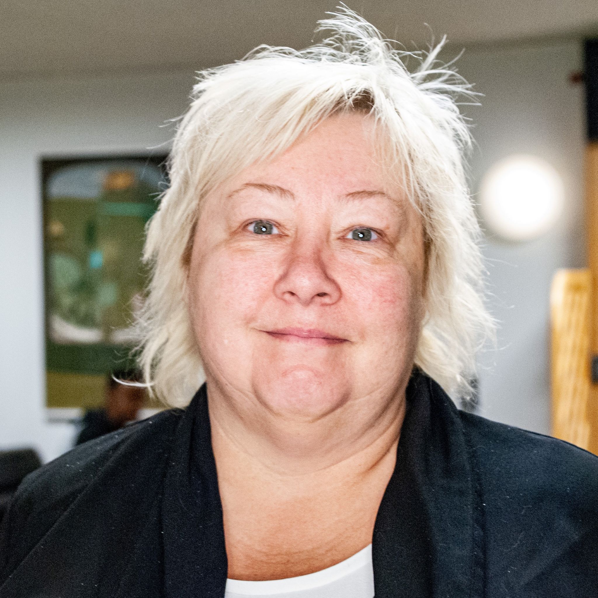 Lisa tittar in i kameran. Hon har vit t-shirt och svart kofta.