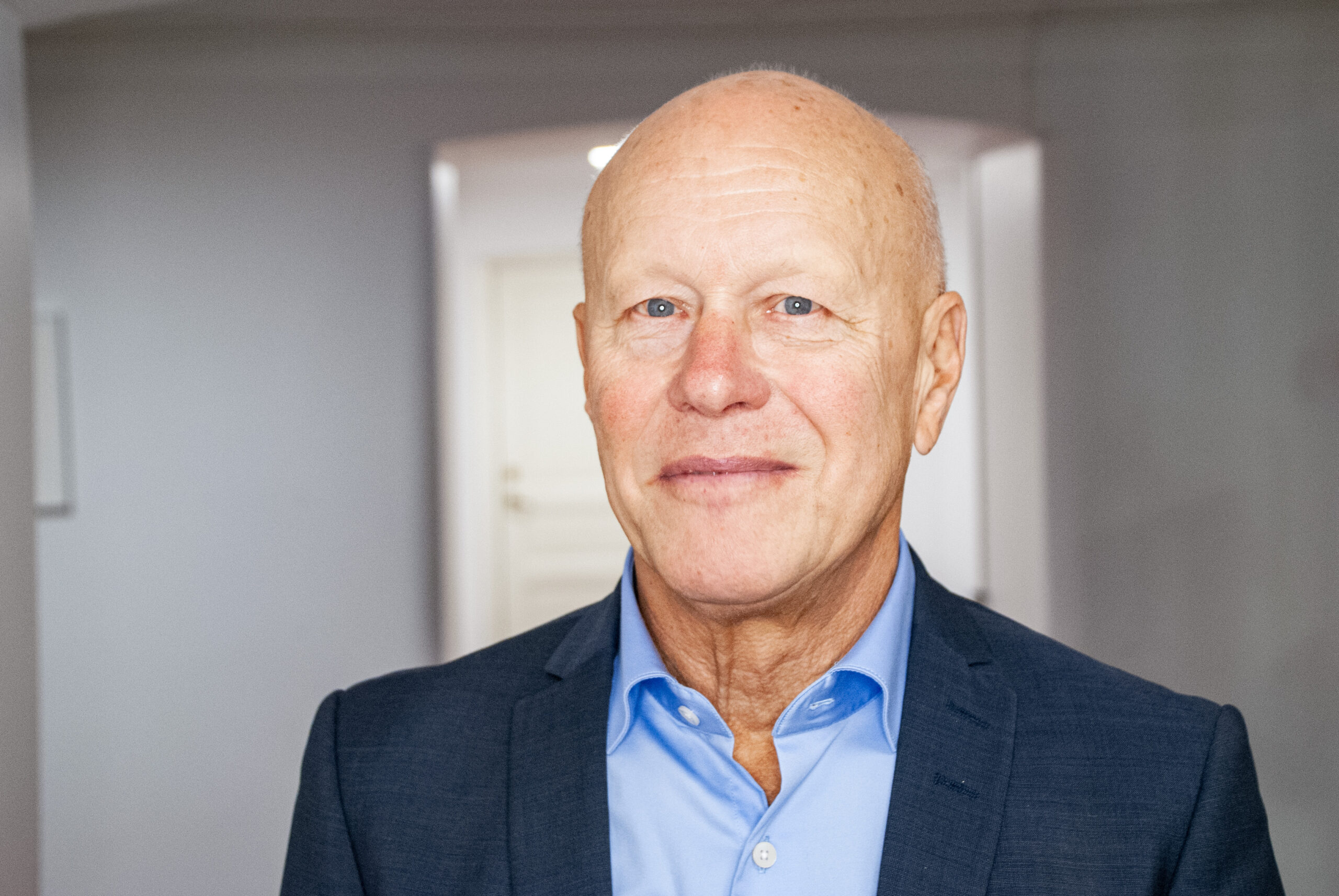 Ulf Brändström tittar in i kameran. Han har på sig en ljusblå skjorta och svart kavaj.